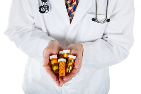 Doctor holding out a variety of full prescription pill bottles
